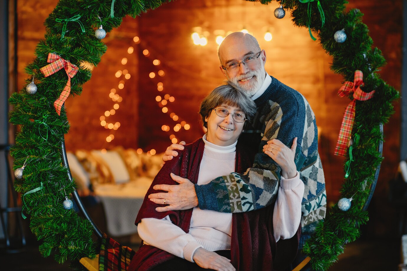 Two adults posing in front of a holiday backdrop.