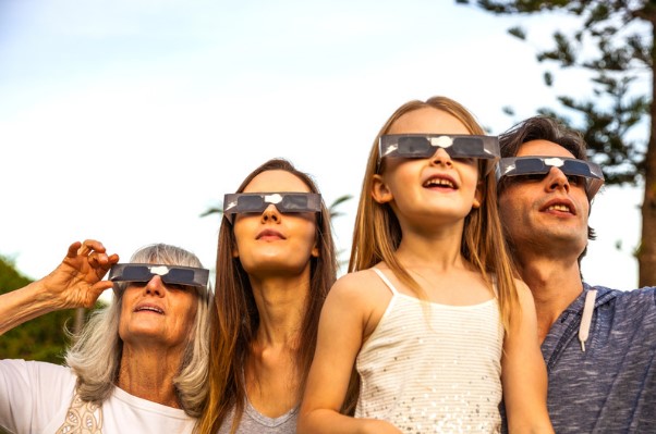Family viewing solar eclipse with glasses.